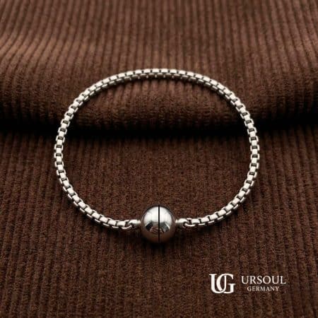 Pulsera Nordik Sphere Silver Plated para caballero en acabado plateado con esfera metálica y cierre de imanes, UrSoul Germany sobre tela café.
