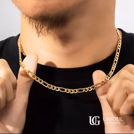 Cadena Fígaro dorada corta para hombre, Gold Color Ursoul Germany, sobre camiseta negra con fondo gris