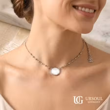 Gargantilla cadena de esferas plateada con medallón de concha nácar para mujer, Silver Plated Ursoul Germany, sobre tela beige y en cuello con fondo de mármol