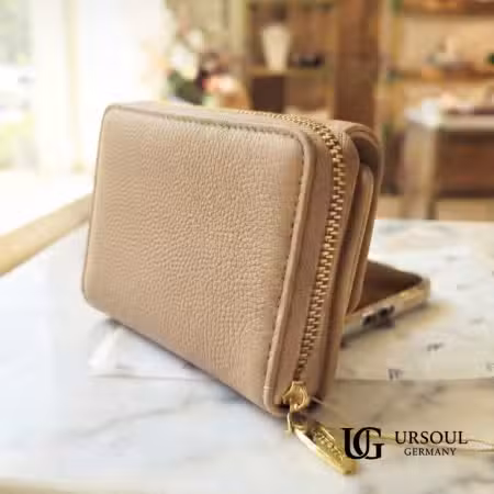 Billetera compacta color champán en piel vegana abierta mostrando interior con broche dorado, elegida por Ursoul Germany.