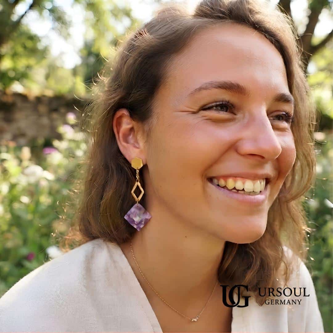 WhatsApp Image 2026-09-13 at 1.38.26 PM Aretes colgantes hexágono dorado con placa mármol lila para mujer, Gold Color Ursoul Germany, sobre tela beige con lavanda y en oreja con fondo de jardín