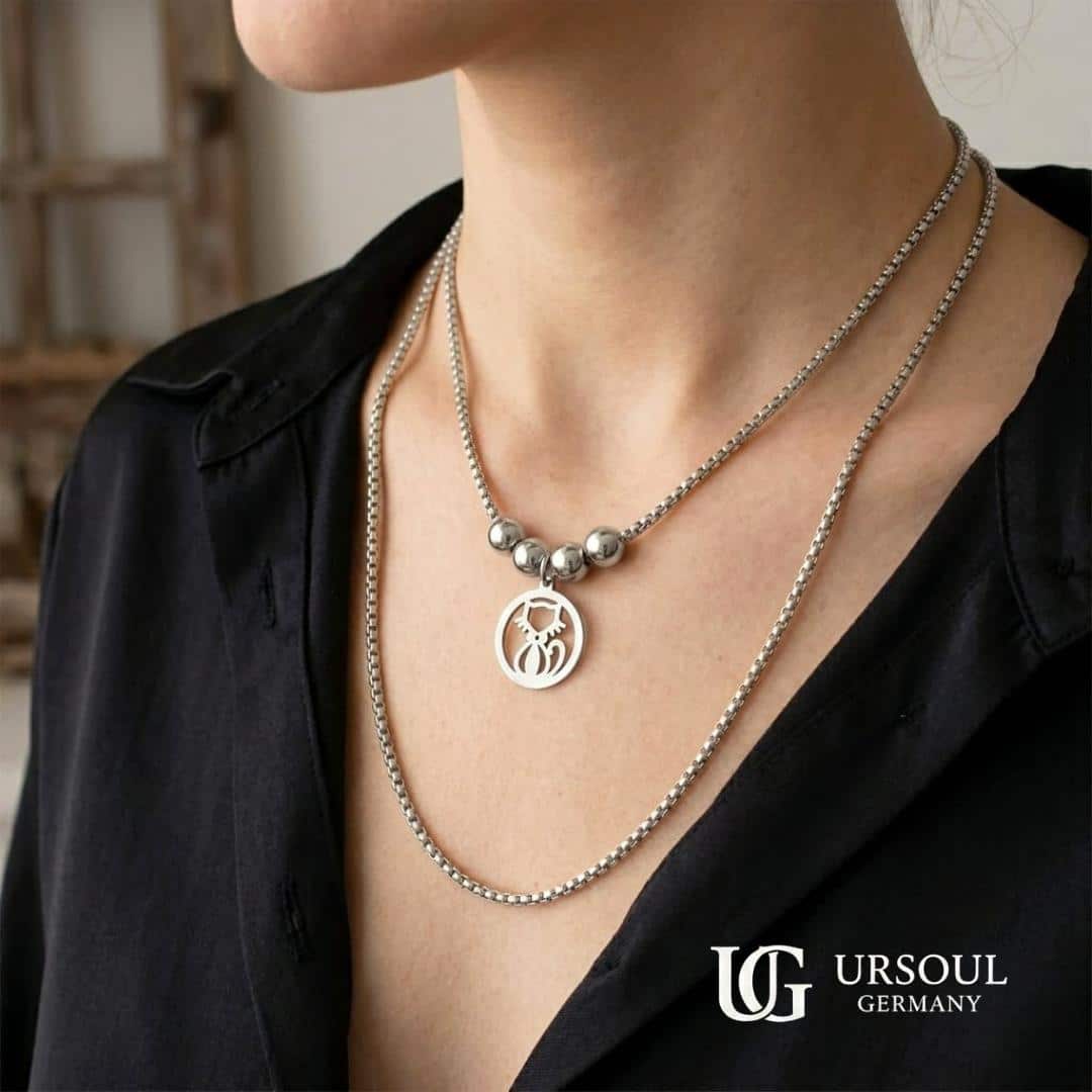 WhatsApp Image 2026-09-13 at 1.38.28 PM (1) Collar doble cadena box plateada con esferas y dije gato calado para mujer, Silver Plated Ursoul Germany, sobre plato blanco y en cuello con camisa negra