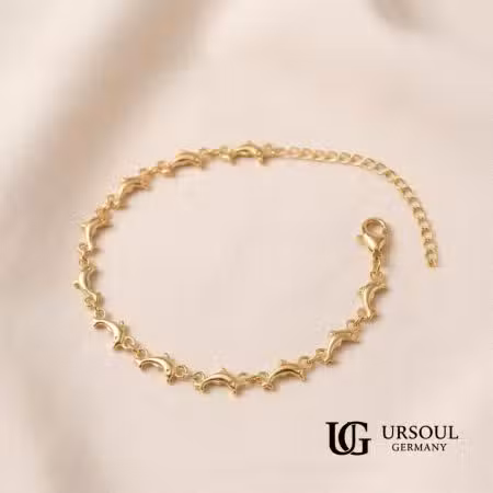 Tobillera eslabones delfines dorada ajustable para mujer, Gold Color Ursoul Germany, sobre tela beige y en tobillo con sandalia nude