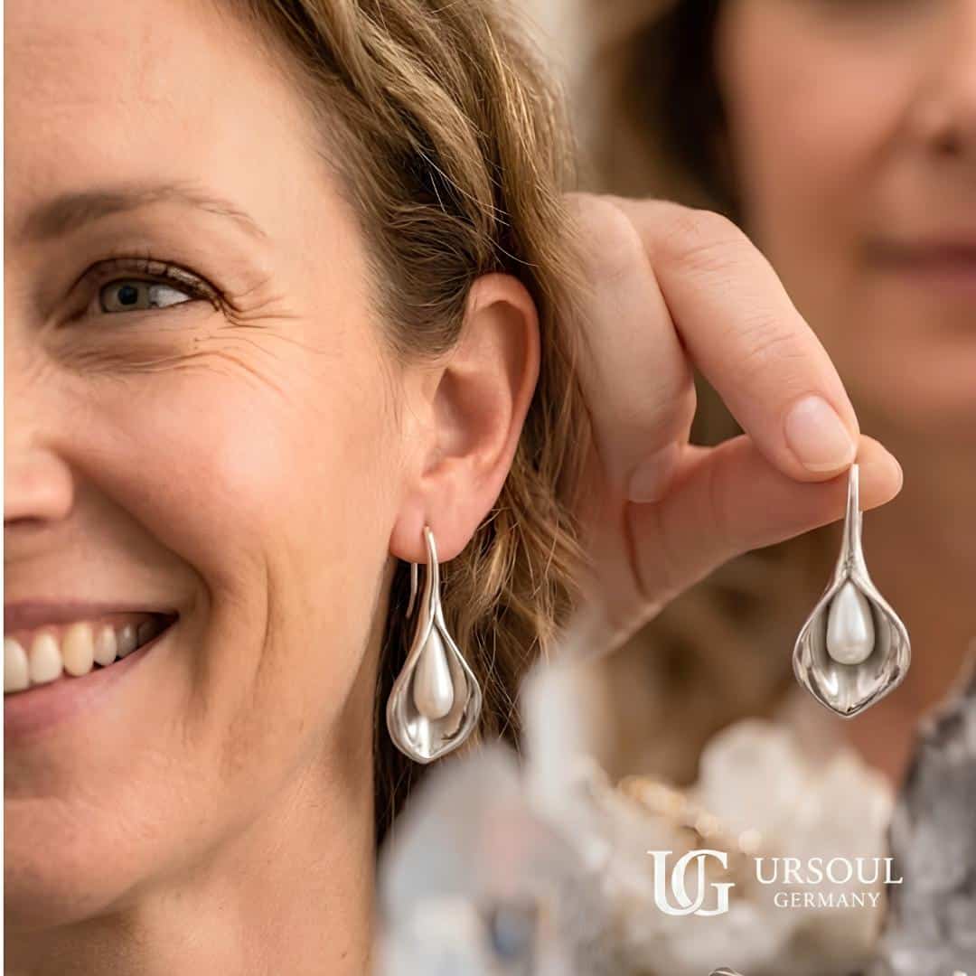 WhatsApp Image 2026-09-13 at 1.38.30 PM (4) Aretes cala plateada con perla de imitación blanca 4.5cm para mujer, Silver Plated Ursoul Germany, sobre estuche beige con hojas verdes y en oreja con sonrisa